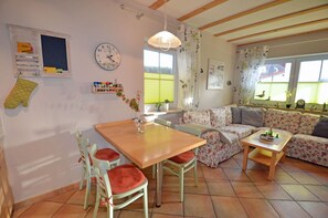Ein gemütliches Wohnzimmer mit einem Holzesstisch, einem floralen Sofa und einem Fenster mit Blick.