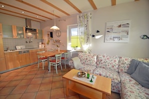 Una cocina acogedora con comedor, un sofá y una mesa con una botella y vasos.
