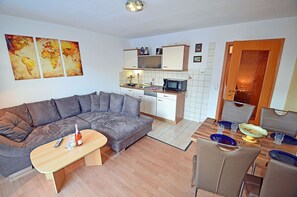 A compact living space with a sofa, a dining table with chairs, a kitchen area with a microwave, and a small cabinet. - Vacation rental just 1,000 meters from the Baltic Sea beach, 1 bedroom, sleeps up to 4 people (Breege)