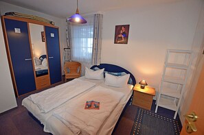 A hotel room with a bed, a wardrobe, a chair, a bedside table with a lamp, and a picture on the wall. - Vacation rental just 1,000 meters from the Baltic Sea beach, 1 bedroom, sleeps up to 4 people (Breege)