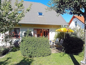 A house with a tiled roof, a small window, and a door. There is a yellow umbrella and a table with chairs outside. - Vacation rental just 1,000 meters from the Baltic Sea beach, 1 bedroom, sleeps up to 4 people (Breege)