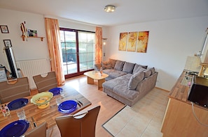 A modern living room with a sofa, dining table, and kitchen area. - Vacation rental just 1,000 meters from the Baltic Sea beach, 1 bedroom, sleeps up to 4 people (Breege)