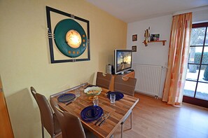A dining area with a wooden table, chairs, a television, and a window with curtains. - Vacation rental just 1,000 meters from the Baltic Sea beach, 1 bedroom, sleeps up to 4 people (Breege)