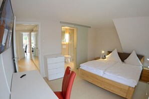 Ein Schlafzimmer mit Bett, Nachttisch, Stuhl und Schreibtisch mit Sitzgelegenheit.