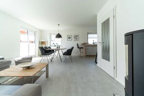 A modern living room with a dining area, a kitchen, and a black refrigerator. - High-end furnishings with a fireplace, about 350 meters from the beach, sleeps up to 6, Wi-Fi (Breege)