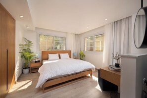 A modern bedroom with a wooden bed, bedside tables, a desk, and a potted plant. - Specail offer at Western by Spacey #10 (Cairo)