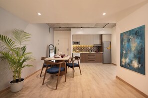 A modern kitchen with a dining area, wooden flooring, and a large abstract painting on the wall. - Specail offer at Western by Spacey #10 (Cairo)