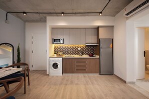 A compact kitchen with a washing machine, microwave, and refrigerator. - Specail offer at Western by Spacey #10 (Cairo)