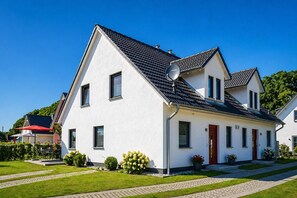 Ett modernt hus i två våningar med ett sluttande tak, en satellitmottagare och en välskött gräsmatta.