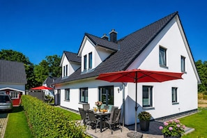 A modern two-story house with a patio area featuring outdoor furniture and red umbrellas. - High-end furnishings with a fireplace, about 350 meters from the beach, sleeps up to 6, Wi-Fi (Breege)