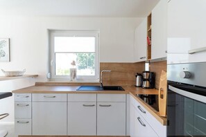 A modern kitchen with a wooden countertop, white cabinetry, and a built-in oven. - High-end furnishings with a fireplace, about 350 meters from the beach, sleeps up to 6, Wi-Fi (Breege)