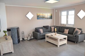 Uma sala de estar com um sofá cinzento, uma mesa de centro de madeira e uma pintura na parede.