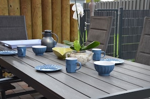 Ein Holztisch mit blauen und weißen Keramiktassen, Tellern und einer weißen Teekanne mit einer grünen Pflanze.