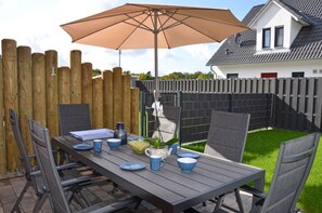 Eine Terrasse im Freien mit Esstisch, umgeben von einem Holzzaun.