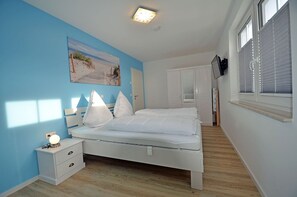 Ein Schlafzimmer mit einem Bett, einem Nachttisch und einem an der Wand befestigten Kunstwerk.