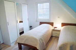 Ein Schlafzimmer mit zwei Betten, einem Fenster und einem Kleiderschrank.