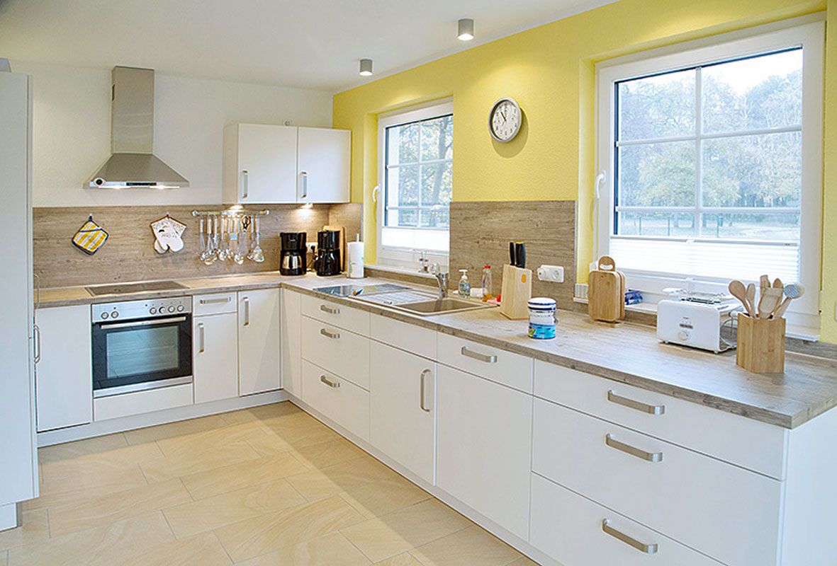 A modern kitchen with white cabinets, a built-in oven, a coffee maker, and a toaster.