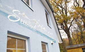 Um edifício com fachada pintada, uma janela e uma árvore com folhas amarelas.
