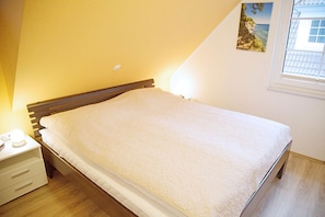 Quarto com cama, mesa de cabeceira e janela com vista.