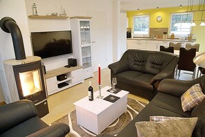 Ein Wohnzimmer mit Kamin, Fernseher, einer Couch und einem Couchtisch mit Flasche und Gläsern.
