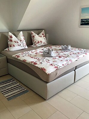 A bedroom with a bed, pillows, a folded towel, and a rug. - Luxurious semi-detached house, about 800 m from the beach, sleeps up to 6, with a sauna and washing machine (Breege)