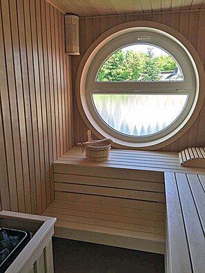 Sauna, jossa on puinen sisustus, ikkuna ja penkki.