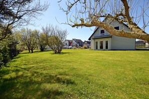 Ein Wohnhaus mit großem Rasen, ein freistehendes Haus und ein Baum im Vordergrund.