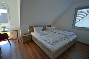 Une chambre à coucher avec un lit en bois, un bureau, une chaise et une fenêtre avec des stores.