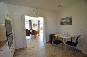 Eine moderne Küche mit integrierten Geräten, eine Essecke mit Tisch und Stühlen sowie ein Bild an der Wand.
