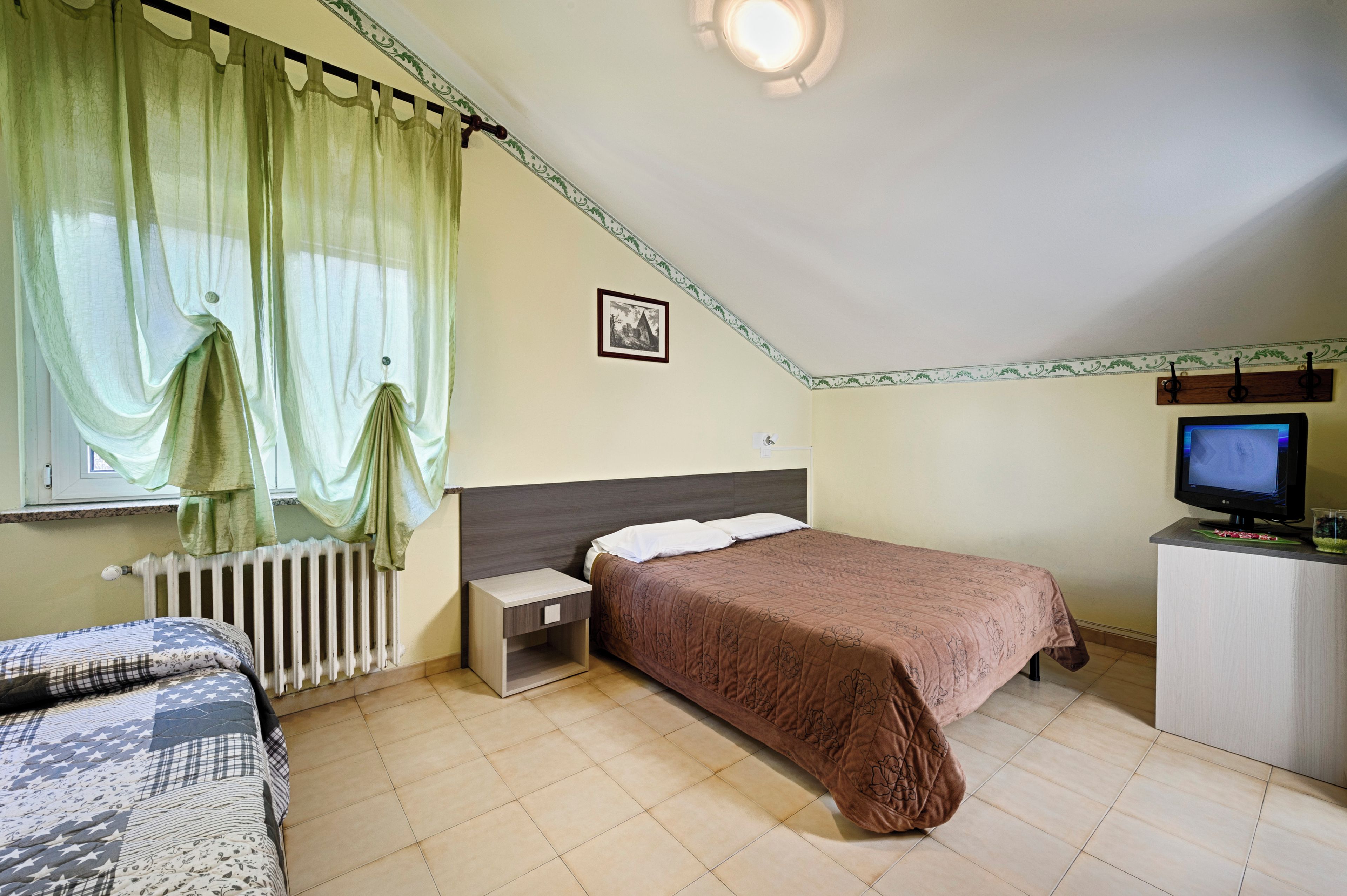 A bedroom with a bed, a nightstand, a television, and a radiator.