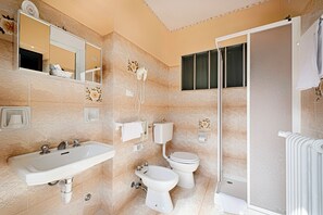 A bathroom with a sink, bidet, toilet, and a shower area. - Albergo Mancuso del Voison (Aosta)