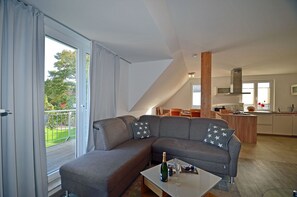 A modern living room with a sectional sofa, a dining area, and a kitchen. - Just 700 meters from the Baltic Sea beach, with a fireplace, Wi-Fi, and a washing machine; sleeps up to 6 people. (Breege)