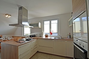 A modern kitchen with a central island, built-in microwave, stainless steel appliances, and a large window providing natural light. - Just 700 meters from the Baltic Sea beach, with a fireplace, Wi-Fi, and a washing machine; sleeps up to 6 people. (Breege)