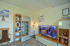A living room with a television, wooden shelves, and a chair. - Just 700 meters from the Baltic Sea beach, with a fireplace, Wi-Fi, and a washing machine; sleeps up to 6 people. (Breege)