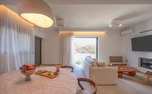 Una sala moderna con una mesa redonda, un sofá, un televisor y un balcón con vistas.