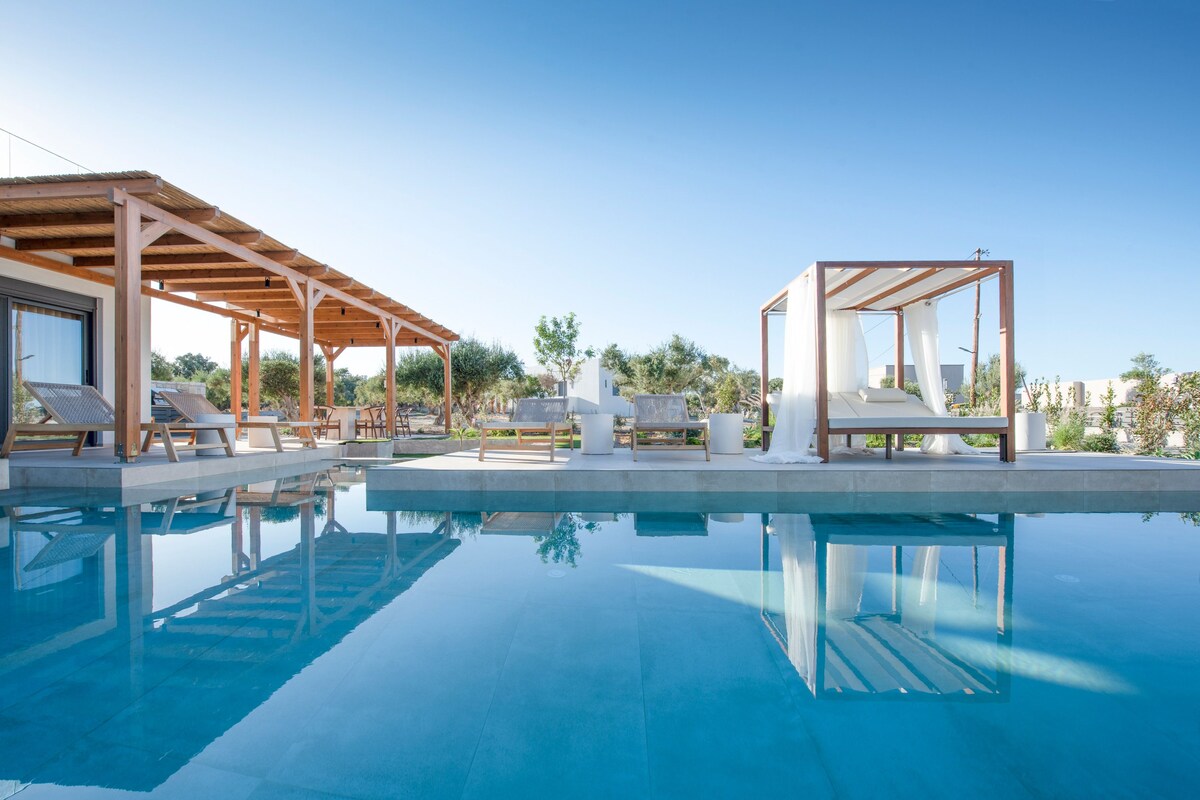 A pool area with wooden pergolas, lounge chairs, and a clear blue sky.
