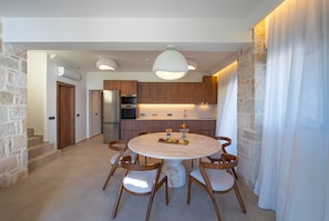 Una cocina moderna con armarios de madera, horno empotrado y comedor con mesa y sillas redondas.
