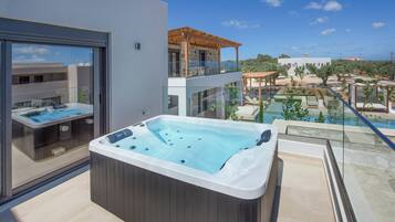 Un jacuzzi moderno al aire libre con cerramiento de vidrio, una zona de piscina con sillas de descanso y vistas a un paisaje desértico.