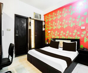 Ein Hotelzimmer mit einem Bett, einem Sessel, einem Schreibtisch mit Telefon und einer Wand mit Blumenmuster.