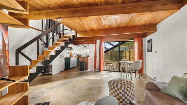 Un intérieur moderne avec un escalier en bois, un coin repas et une cuisine.