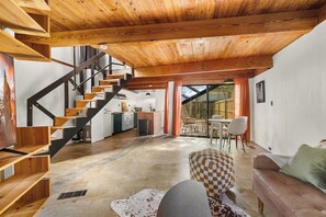 A modern interior with a wooden staircase, a dining area, and a kitchen.