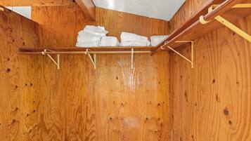 A wooden room with a ceiling and a shelf holding folded towels.