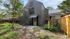 Une maison moderne à deux étages, dotée d’un toit en pente, d’une porte d’entrée et d’une porte de garage visible.