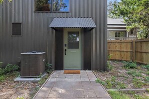 Un edificio residencial con fachada de metal, una puerta verde y un pequeño porche.