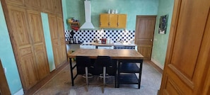 Une cuisine de taille réduite, avec une table et des chaises en bois, une cuisinière et un dosseret à carreaux.