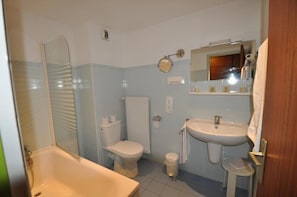 A bathroom with a bathtub, toilet, sink, and a mirror.