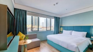 A hotel room with a bed, a seating area, a window with curtains, and a city view. - Spring Sunlight (Xiamen)