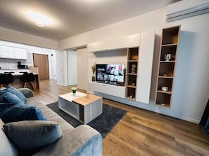 Una sala de estar moderna con sofá, mesa de centro, televisor y estanterías empotradas.