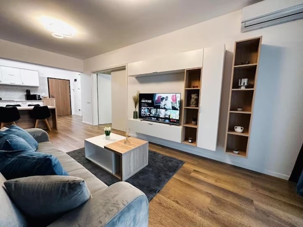 A modern living room with a sofa, coffee table, TV, and built-in shelving.