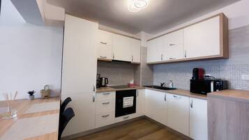 Een moderne keuken met witte kasten, een zwarte oven, een koffiezetapparaat en een spoelbak.